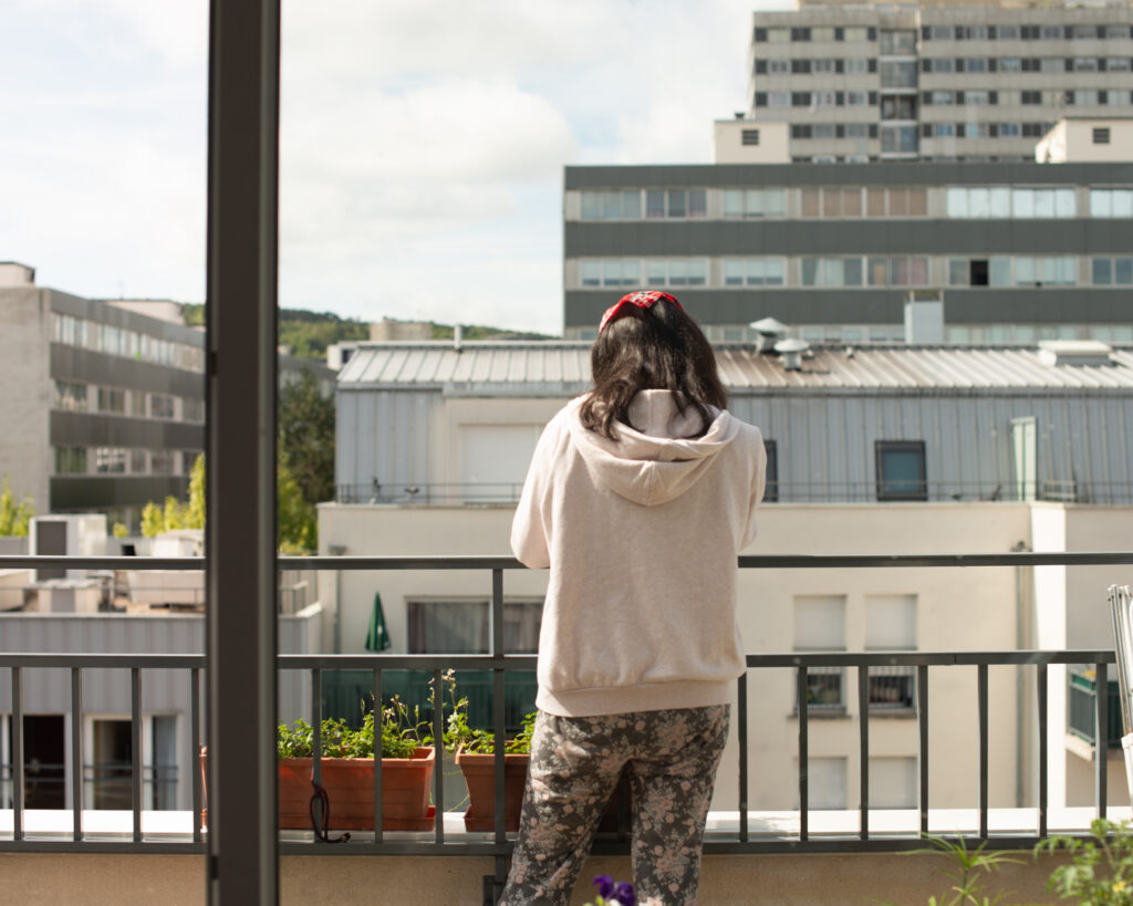 Yara sur le balcon de son appartement, entourée de grands immeubles