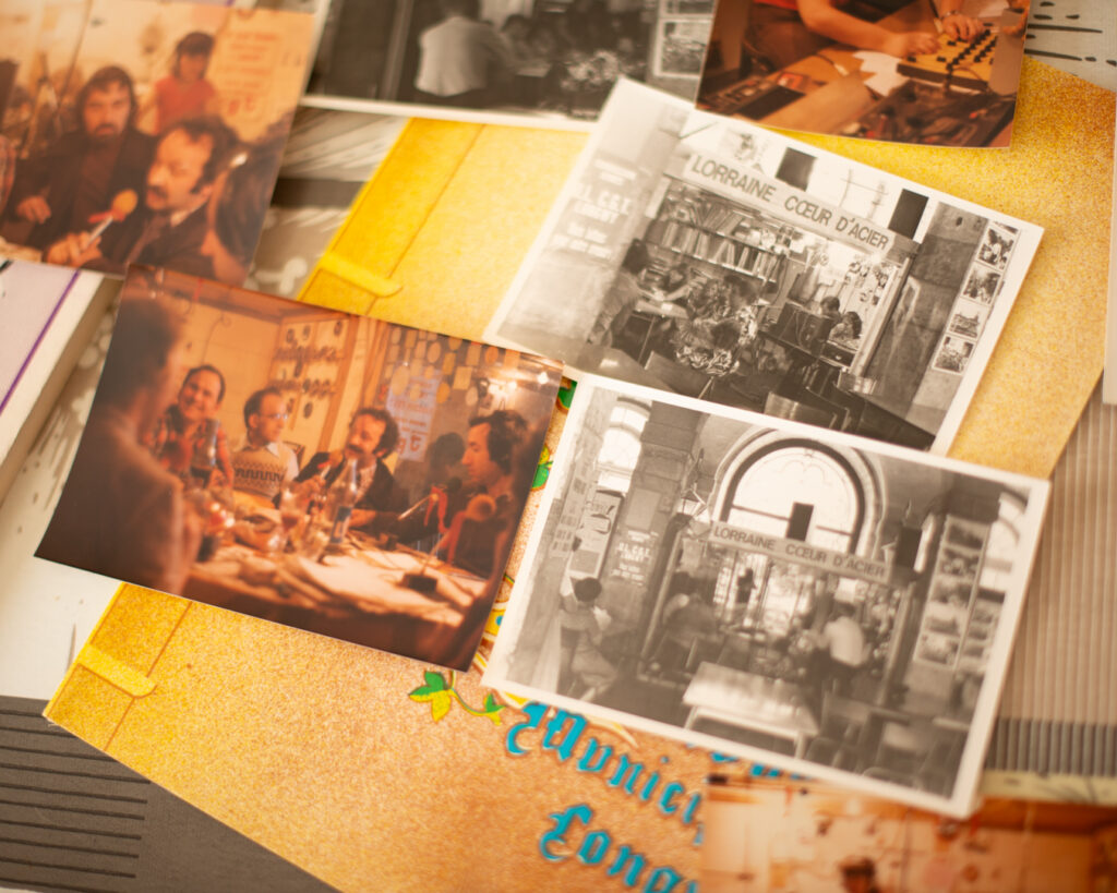 Ensemble de photographies anciennes de la radio Lorraine Coeur d'Acier, disposées sur une table, images d’archives liées à la vie locale et à l’histoire sociale, mémoire collective et transmission.
