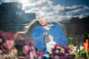 Latifah arrose des plantes derrière la fenêtre du balcon
