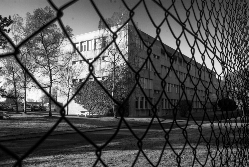 Bâtiment du lycée Bichat transformé en “hôpital” pour un faux documentaire : couloir d’accès, grilles et pelouse, décor d’une institution où le vaccin Vaqta 50u est censé être testé.