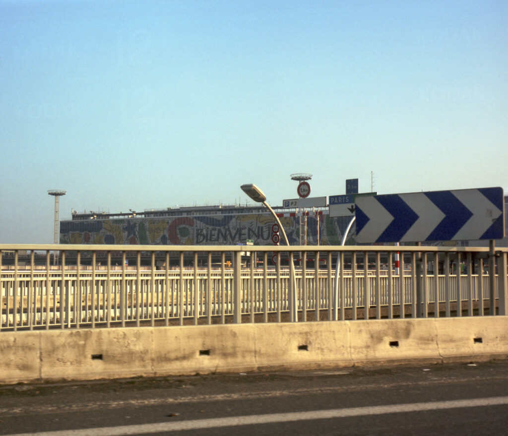 Image de l’aéroport d’Orly le jour de l’arrivée de la famille, avec le mot « Bienvenue » affiché en grand