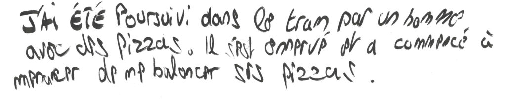 graffiti au marqueur noir, écriture rapide, il est inscrit : J'ai été poursuivi dans le tram par un homme avec des pizzas. Il est arrivé et a commencé à me menacer de me balancer des pizzas.